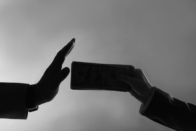 Photo of Silhouettes of man refusing to take bribe from businesswoman on dark grey background, closeup
