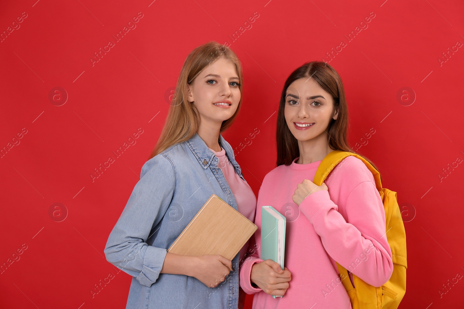 Photo of Teenage students with stationery and backpack on red background