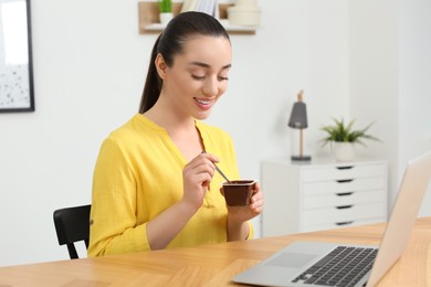 Photo of Happy woman with tasty yogurt in office
