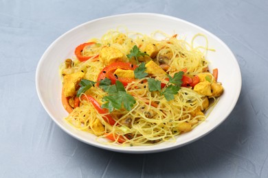 Photo of Stir-fry. Delicious cooked noodles with chicken and vegetables in bowl on gray table, closeup