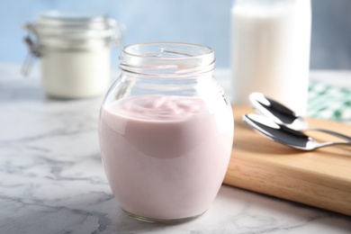 Photo of Glass jar of fresh yogurt on table