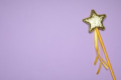 Photo of Beautiful golden magic wand on lilac background, top view. Space for text