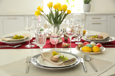 Photo of Festive Easter table setting with floral decor in kitchen