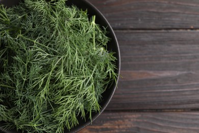 Photo of Bowl of fresh dill on wooden table, top view. Space for text