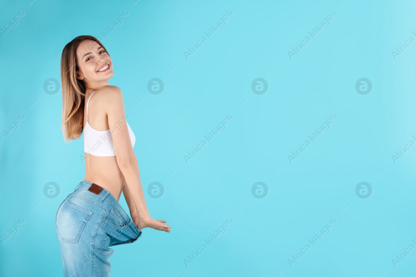 Photo of Slim woman in oversized jeans on color background, space for text. Perfect body