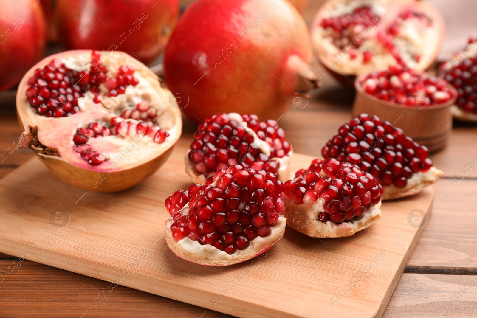 Photo of Delicious fresh ripe pomegranates on wooden table