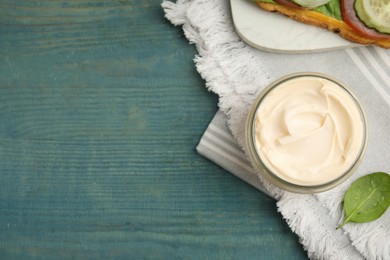 Jar of delicious mayonnaise on light blue wooden table, flat lay. Space for text