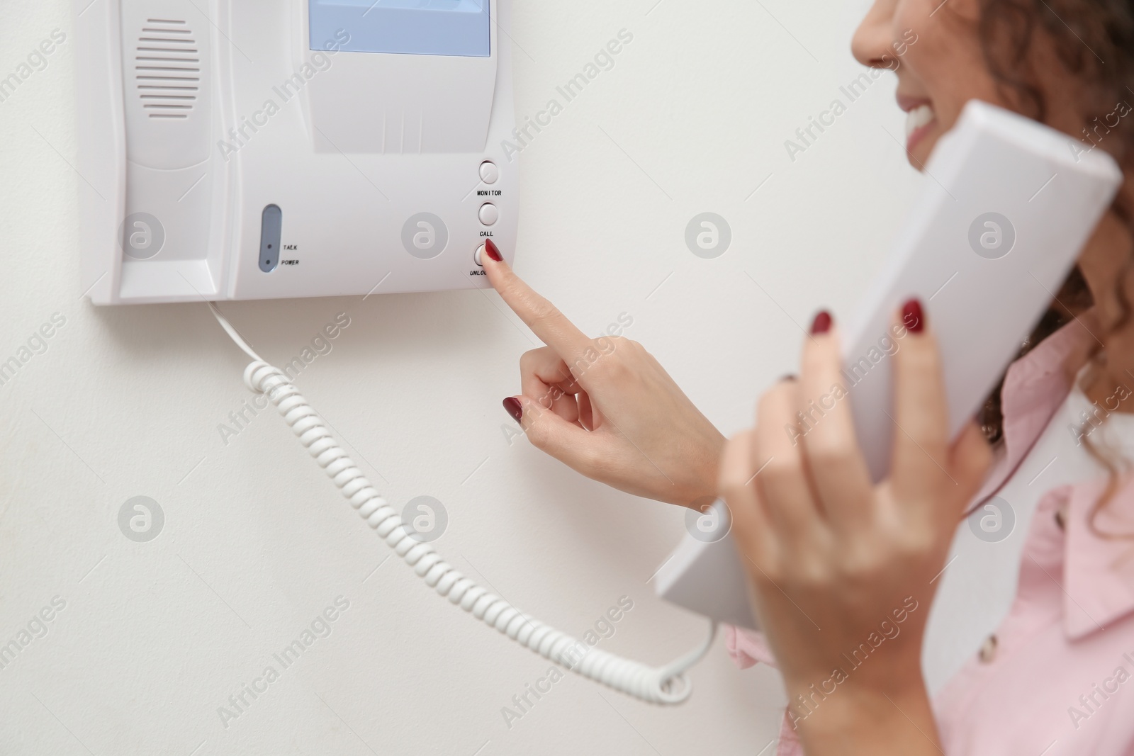 Photo of African-American woman pressing button on intercom panel indoors, closeup