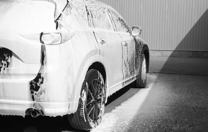 Luxury automobile covered with foam at car wash