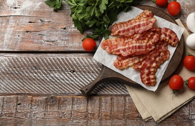 Photo of Fried bacon slices, tomatoes and parsley on wooden rustic table, flat lay. Space for text
