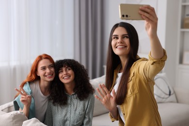 Photo of Happy young friends taking selfie at home, selective focus