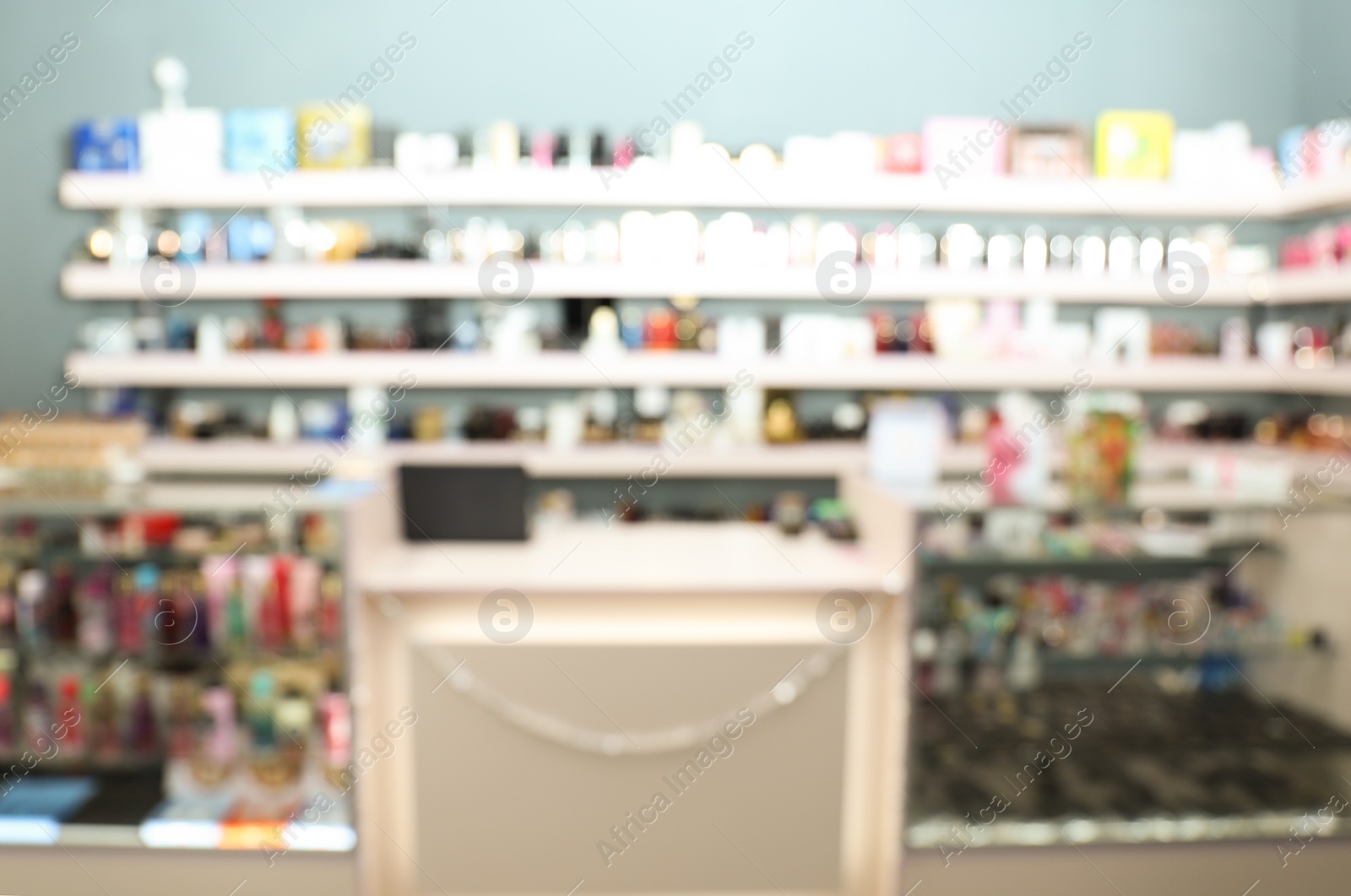 Photo of Blurred view of counter and shelves with perfume bottles in shop