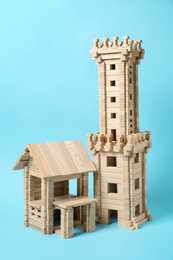 Photo of Wooden tower and house on light blue background. Children's toy