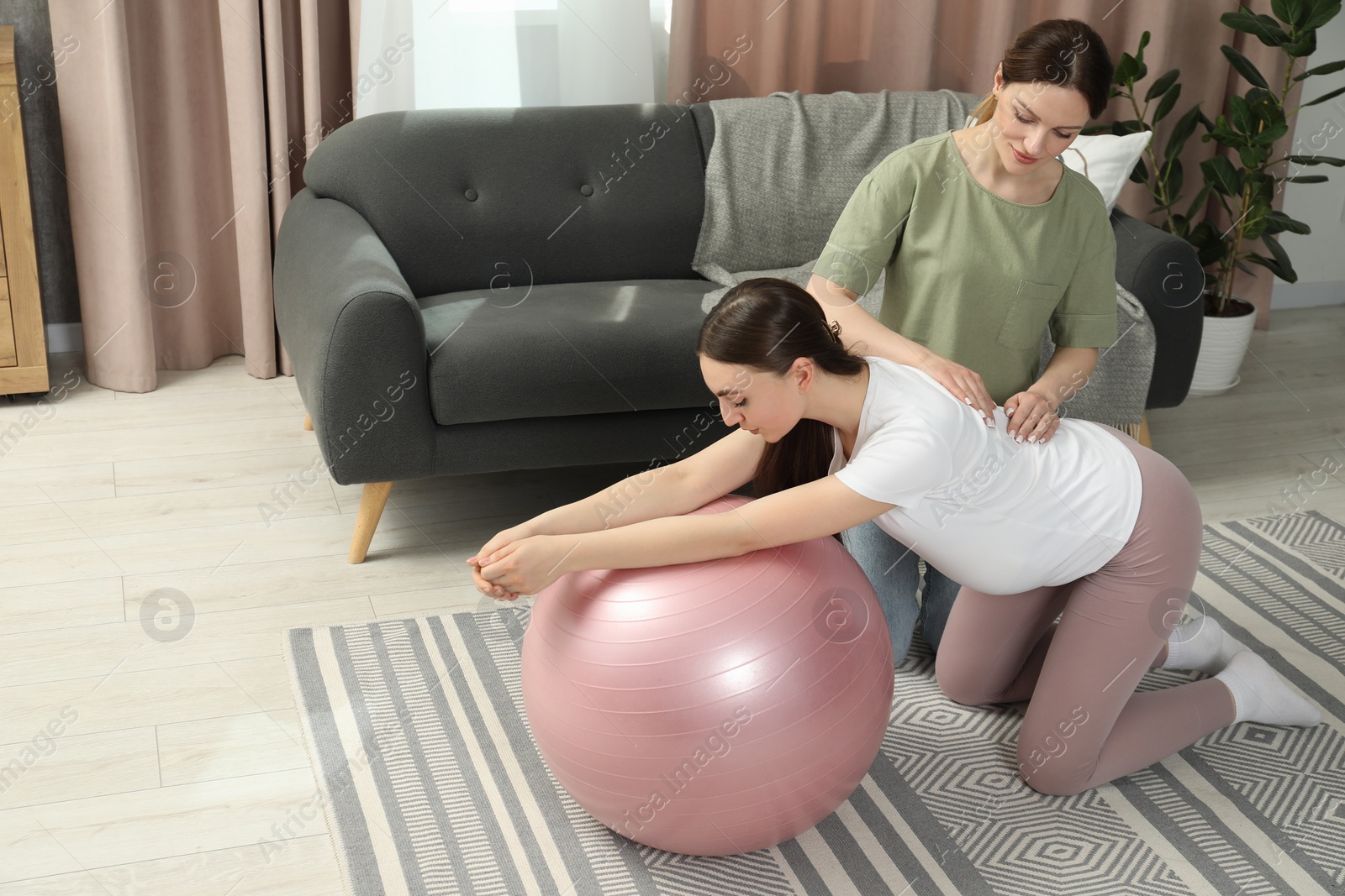 Photo of Doula massaging pregnant woman at home. Preparation for child birth