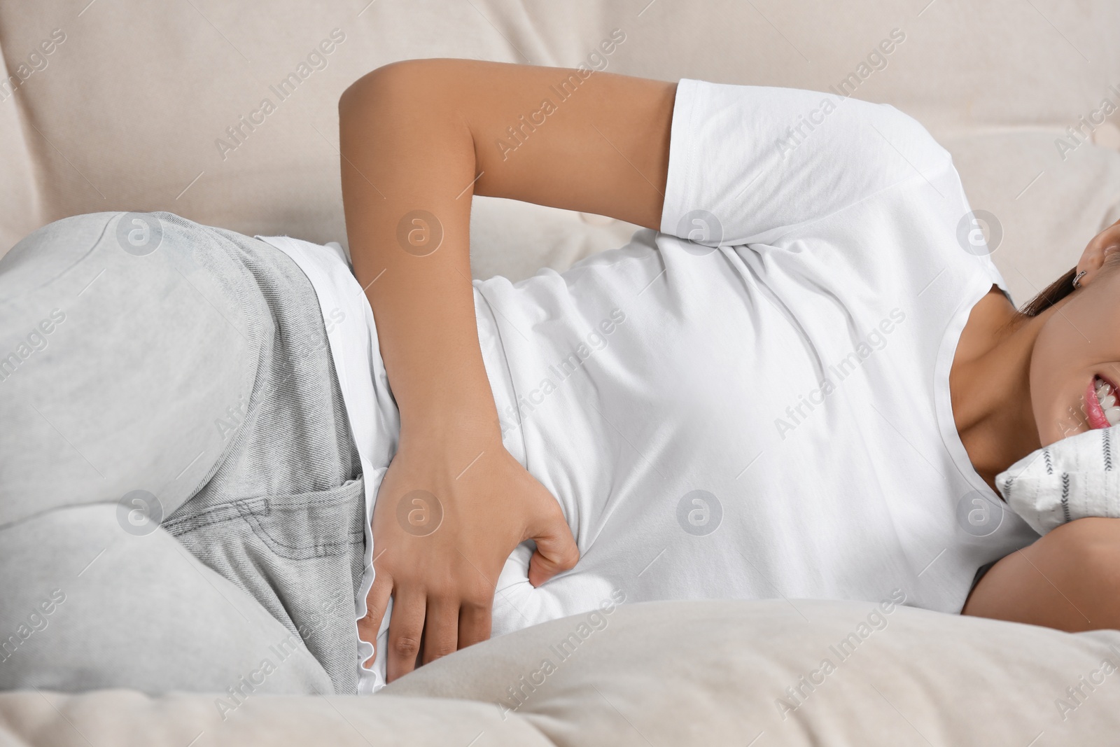 Photo of Young woman suffering from menstrual pain on sofa, closeup