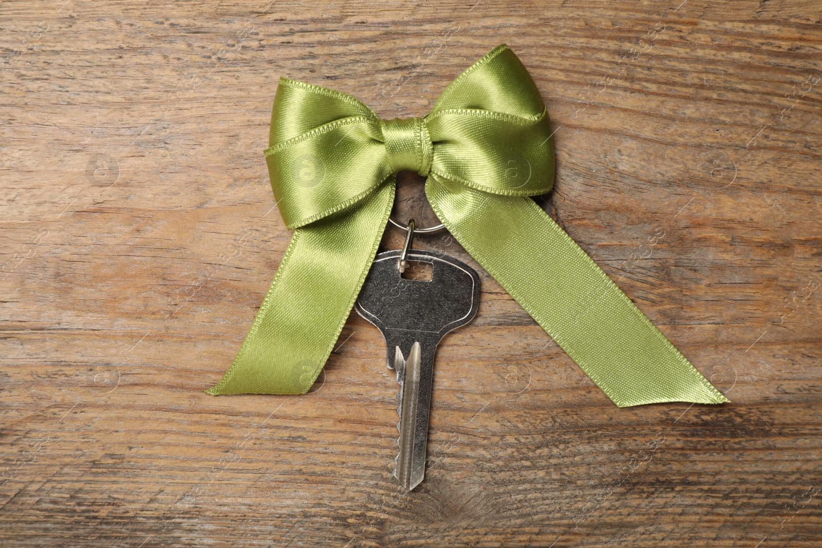 Photo of Key with bow on wooden table, top view. Housewarming party