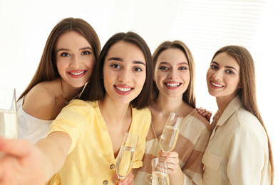 Photo of Beautiful young ladies with champagne taking selfie indoors. Woman's Day