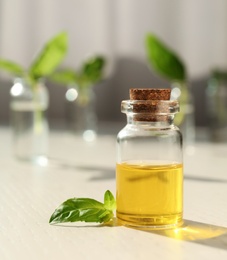 Photo of Bottle of essential basil oil on table against blurred background. Space for text