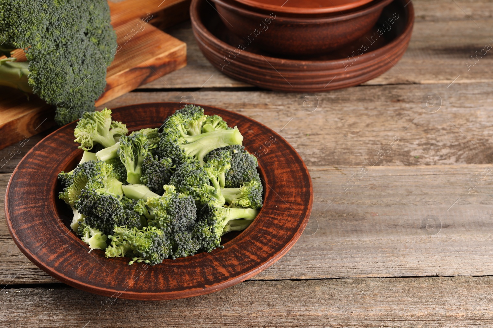 Photo of Plate with fresh raw broccoli on wooden table, space for text