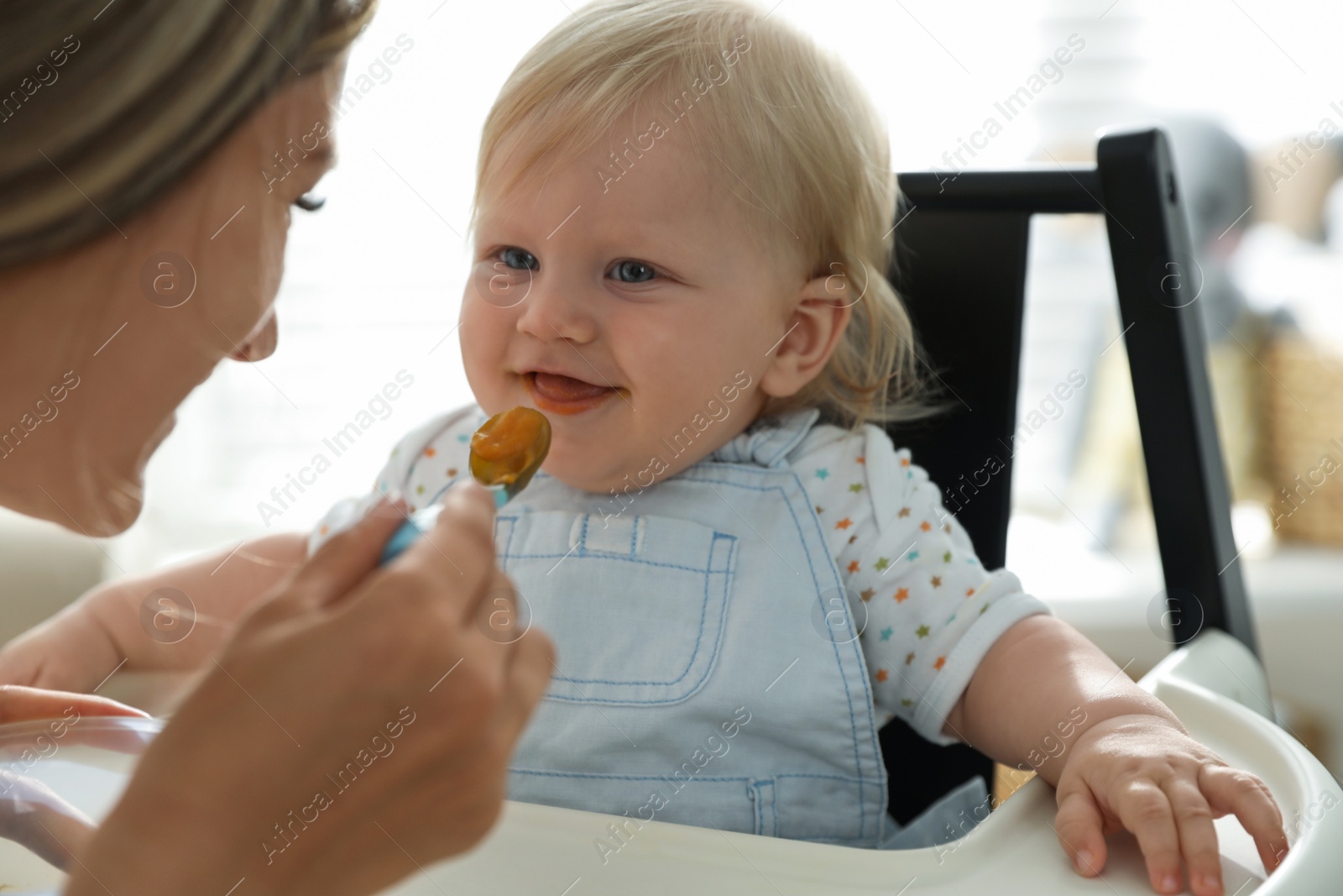 Photo of Mother feeding her cute little baby with healthy food at home