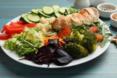 Photo of Balanced diet and healthy foods. Plate with different delicious products on light blue wooden table, closeup