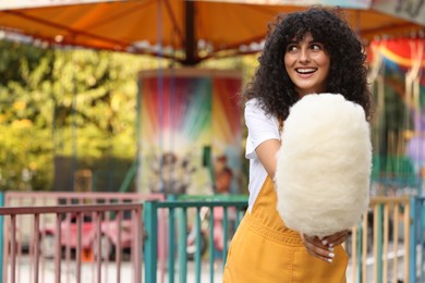 Photo of Smiling woman with cotton candy at funfair. Space for text