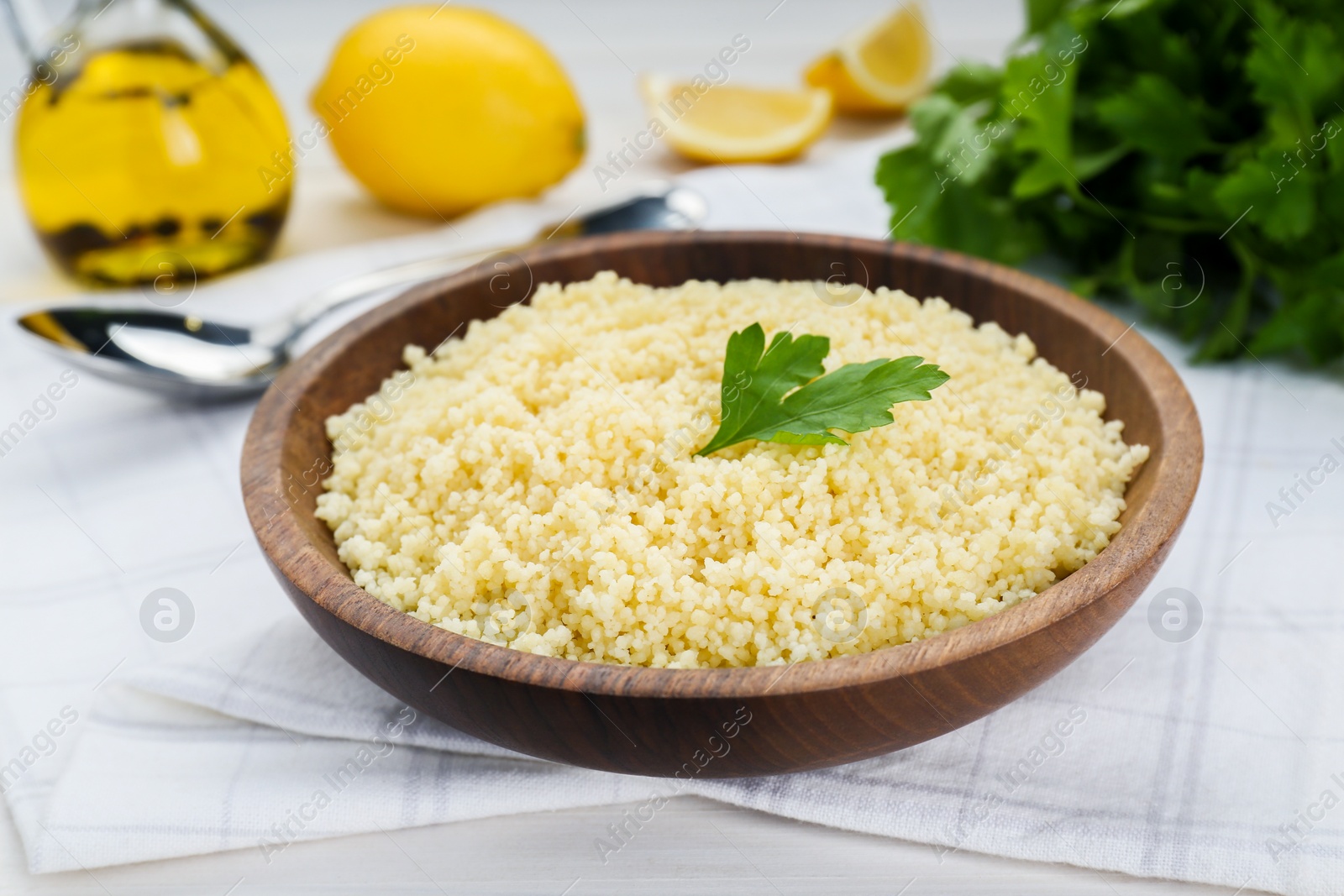 Photo of Tasty couscous with parsley on white wooden table, closeup
