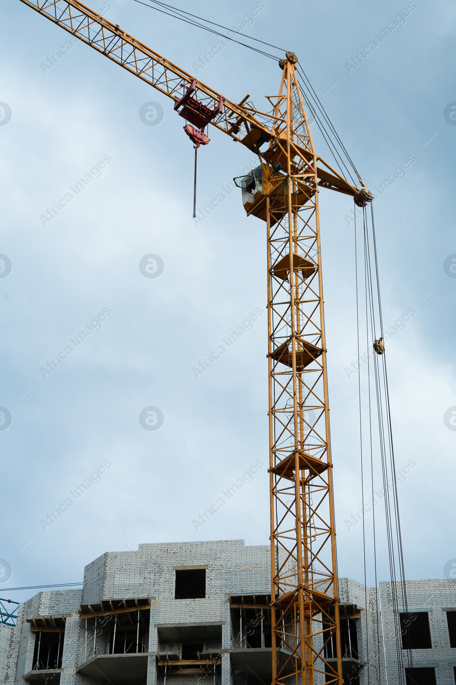 Photo of Construction site with tower crane near unfinished building, low angle view