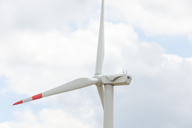 Photo of Modern wind turbine against cloudy sky, closeup. Alternative energy source