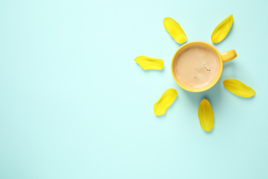 Cup of morning coffee and tulip petals on light blue background, flat lay. Space for text