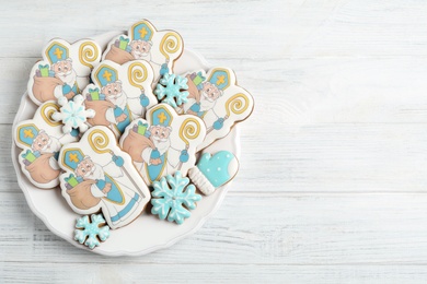 Photo of Tasty gingerbread cookies on white wooden table, top view with space for text. St. Nicholas Day celebration