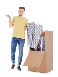 Photo of Young emotional man near wardrobe box on white background