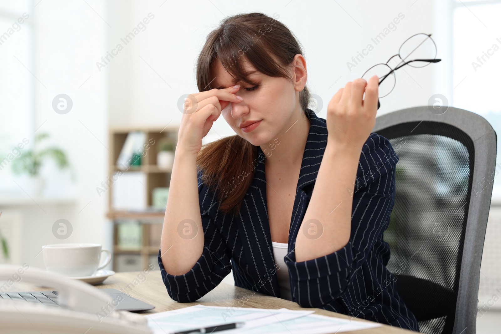 Photo of Overwhelmed woman with glasses suffering at table in office