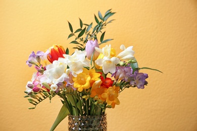 Photo of Glass vase with beautiful freesia on color background