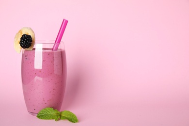 Photo of Glass of delicious blackberry smoothie on pink background. Space for text