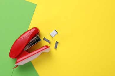 Photo of Red stapler with staples on color background, flat lay. Space for text