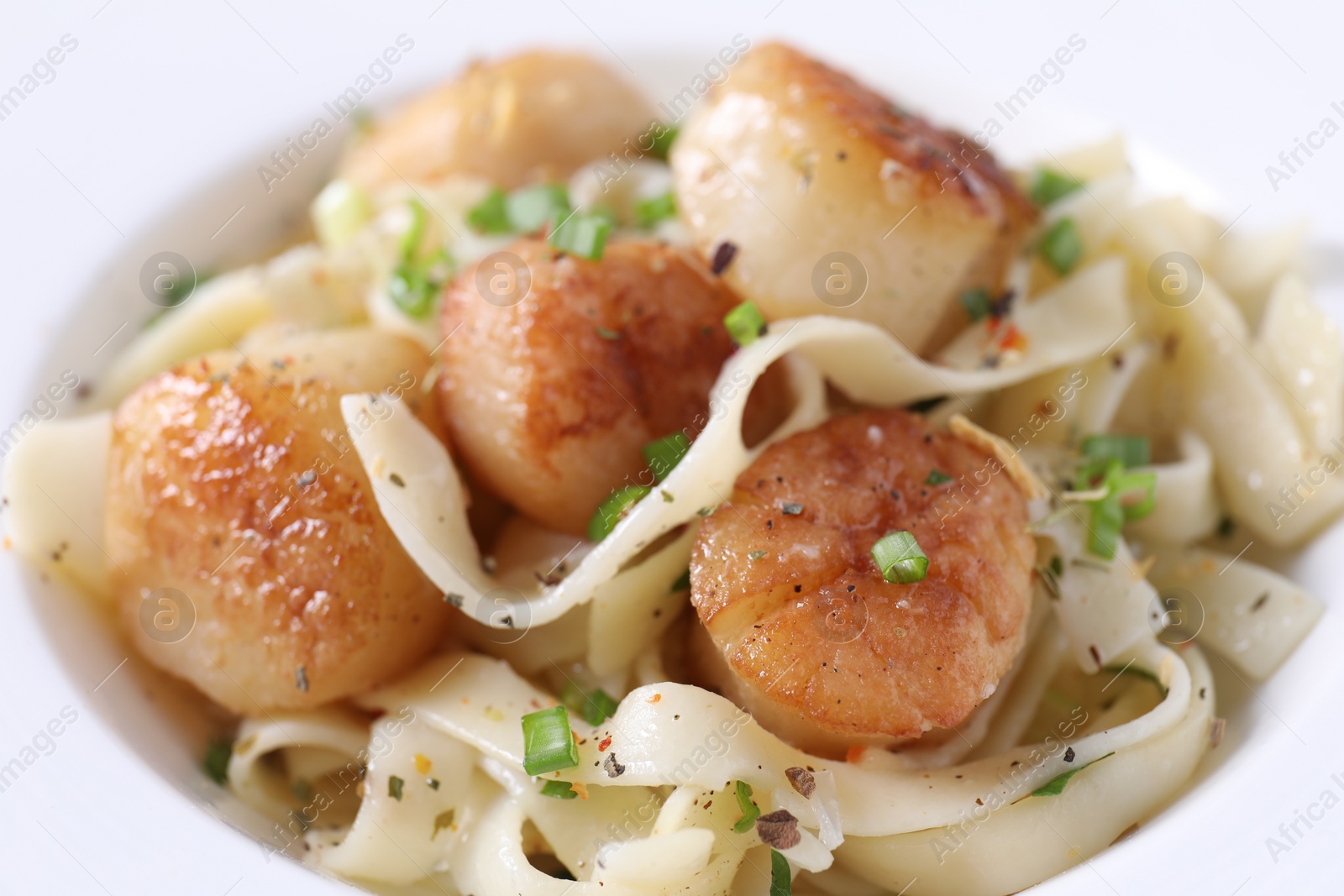 Photo of Delicious scallop pasta with spices in bowl, closeup