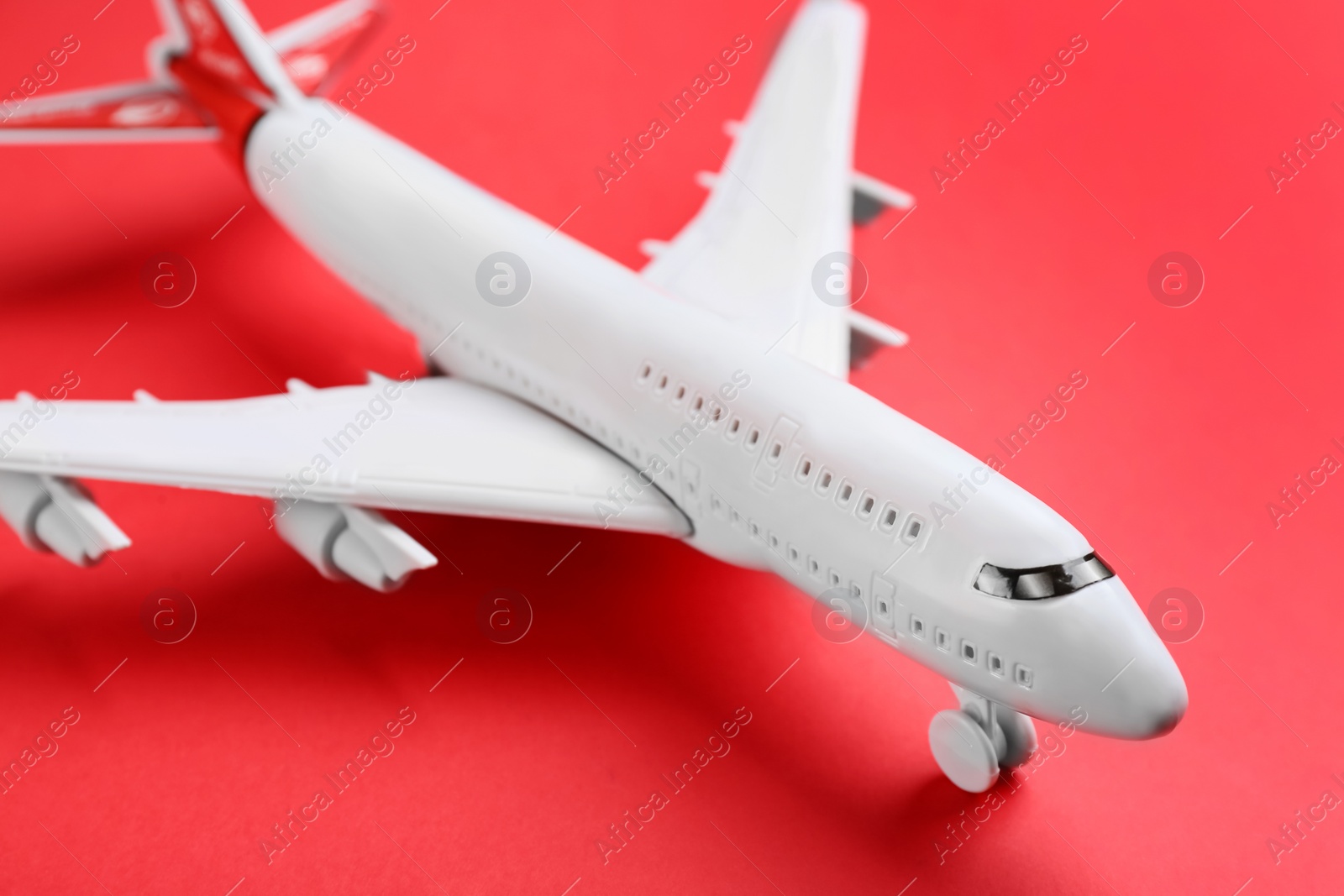 Photo of Toy airplane on red background, closeup view