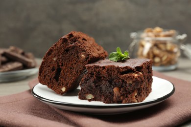 Delicious brownies with nuts and mint on table, closeup