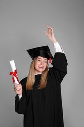 Photo of Happy student with diploma on grey background