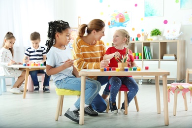 Children with female teacher at painting lesson indoors