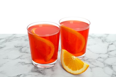 Photo of Aperol spritz cocktail and orange slices in glasses on marble table against white background