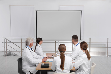 Photo of Team of doctors using video projector during conference indoors