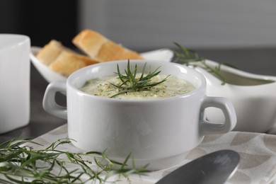 Photo of Delicious cream soup with tarragon, spices and potato in bowl on table, closeup