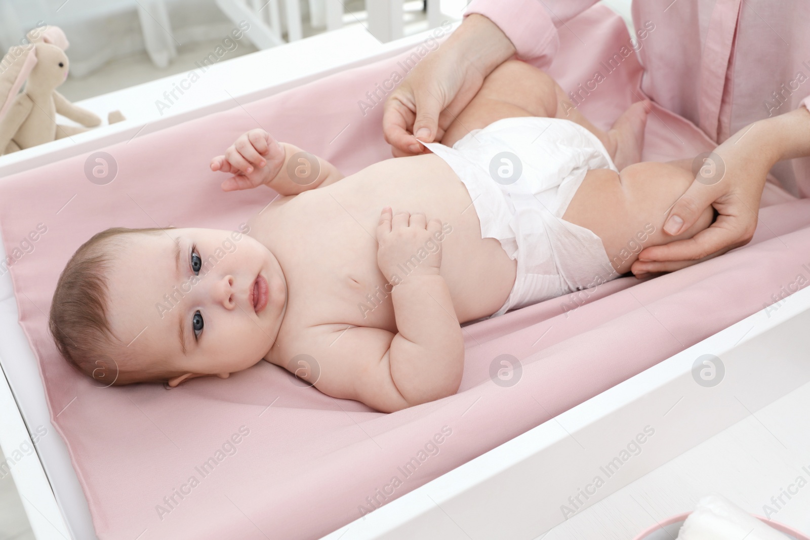 Photo of Mother changing baby's diaper on table at home