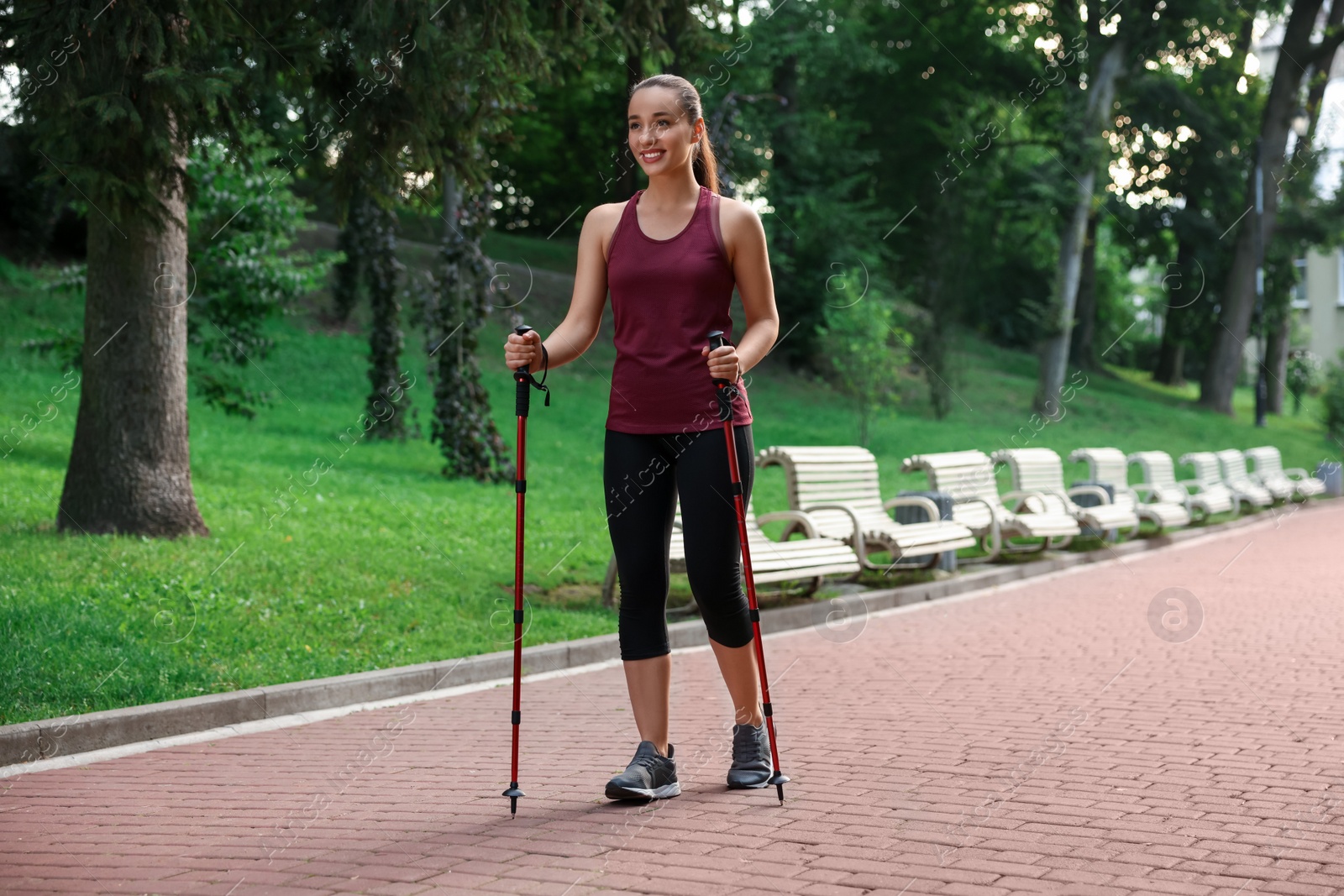 Photo of Young woman practicing Nordic walking with poles outdoors