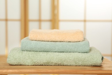 Photo of Soft folded colorful terry towels on wooden table indoors