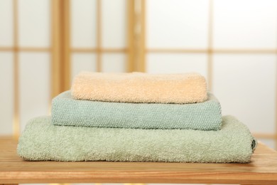 Soft folded colorful terry towels on wooden table indoors