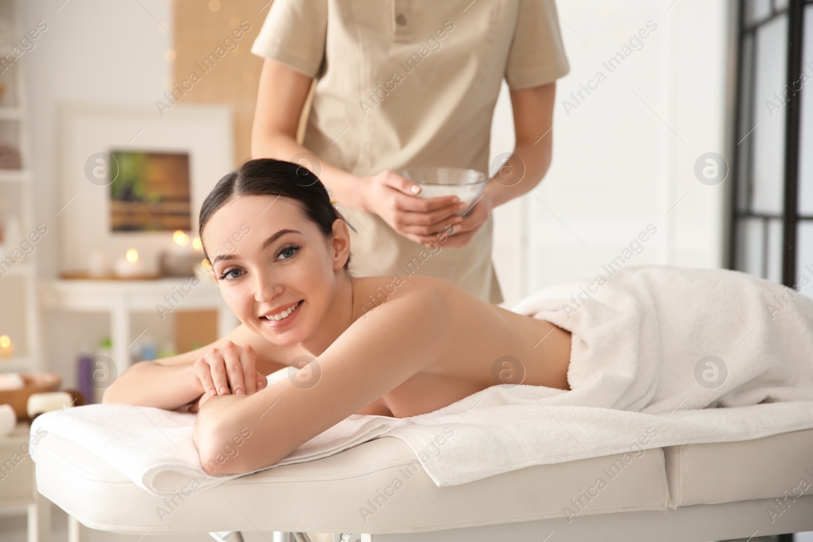 Photo of Beautiful young woman having massage with body scrub in spa salon