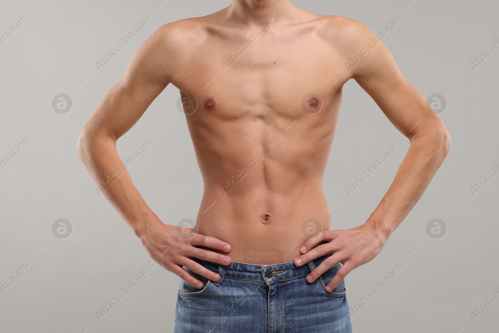 Photo of Shirtless man with slim body on grey background, closeup